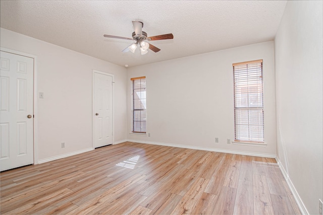 unfurnished room with light wood-style floors, baseboards, ceiling fan, and a healthy amount of sunlight