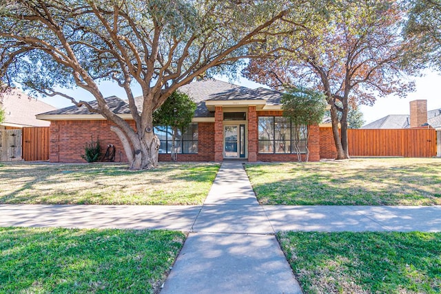 view of front of property featuring brick siding, a gate, a front lawn, and fence