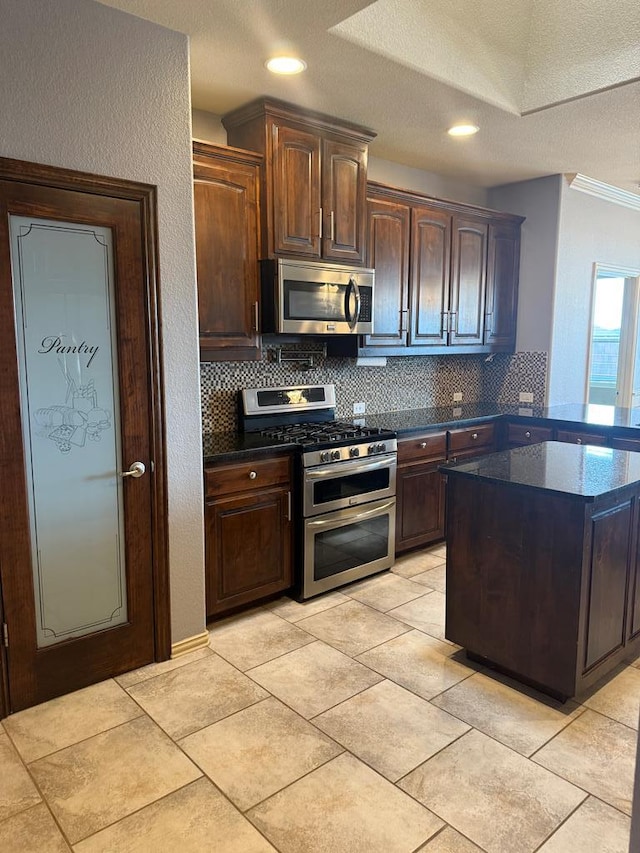 5702 San Miguel Ave, Midland, TX 79705 - kitchen with appliances with stainless steel finishes, decorative backsplash, dark brown cabinets, dark stone countertops, and recessed lighting