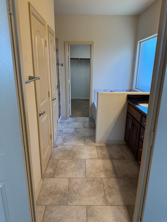 5702 San Miguel Ave, Midland, TX 79705 - full bathroom featuring vanity, stone finish floors, a shower stall, and a spacious closet