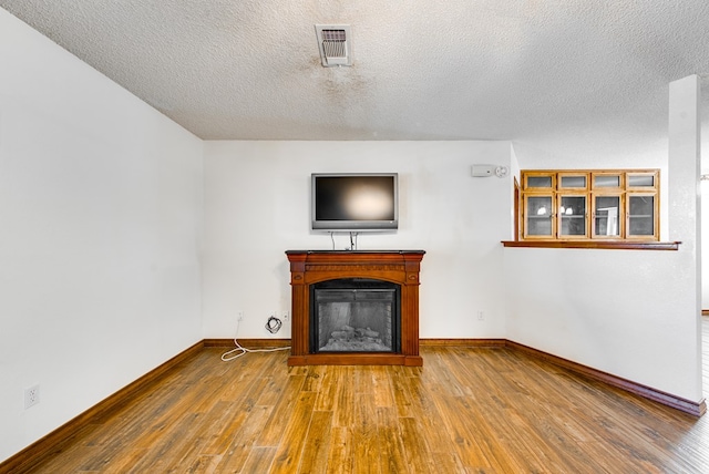 unfurnished living room featuring hardwood / wood-style floors and a textured ceiling