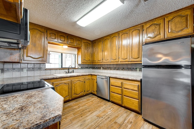 4600 S County Rd 1185, Midland, TX 79706 - kitchen featuring brown cabinetry, light wood-type flooring, tasteful backsplash, a sink, and stainless steel appliances
