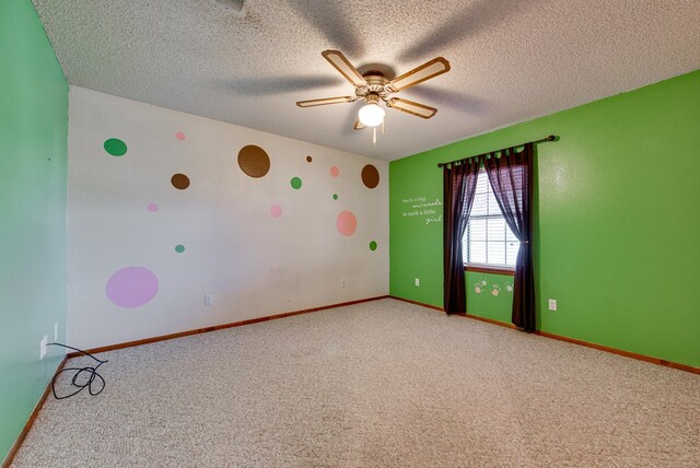 carpeted spare room featuring a textured ceiling, baseboards, and ceiling fan