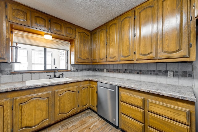 kitchen with backsplash, sink, stainless steel dishwasher, and light hardwood / wood-style floors