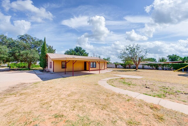 view of front of house with a patio area, metal roof, and fence