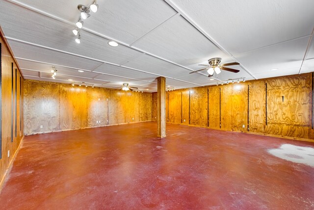 finished basement featuring wooden walls and ceiling fan