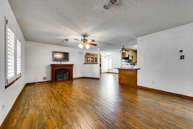 4600 S County Rd 1185, Midland, TX 79706 - unfurnished living room featuring visible vents, a ceiling fan, a glass covered fireplace, and dark wood-style floors