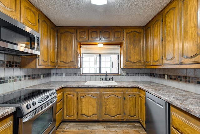 kitchen featuring tasteful backsplash, sink, stainless steel appliances, and light wood-type flooring