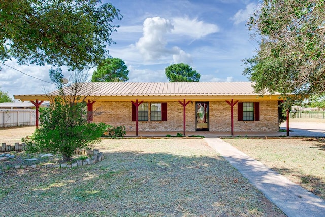 ranch-style house with metal roof, brick siding, a porch, and fence