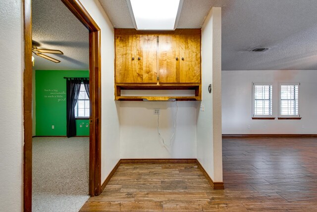 interior space with baseboards, a textured ceiling, and wood finished floors