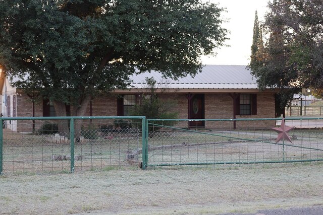 view of front facade with fence, brick siding, and metal roof