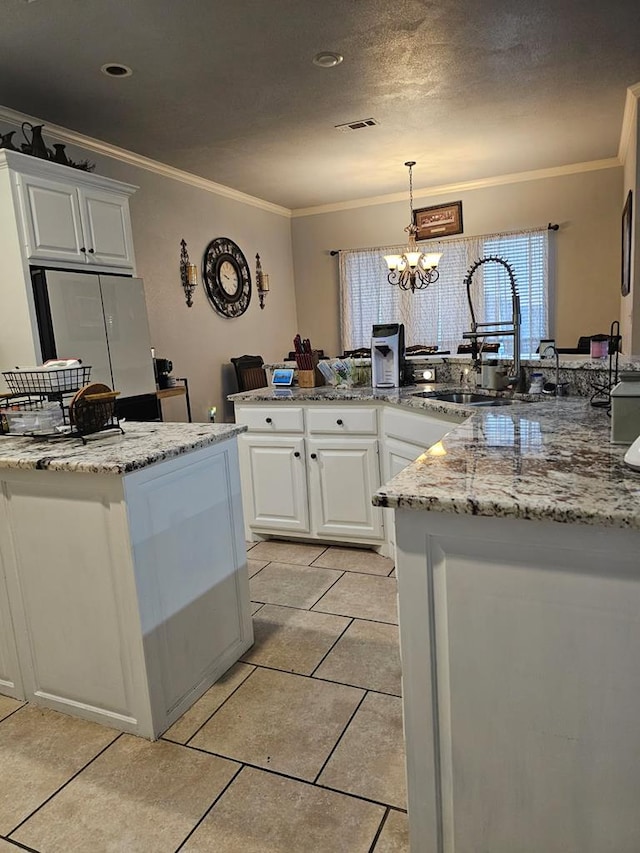 kitchen featuring sink, crown molding, white cabinetry, light stone countertops, and decorative light fixtures