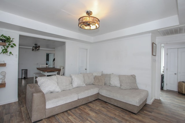 living room with a raised ceiling, wood finished floors, visible vents, and baseboards