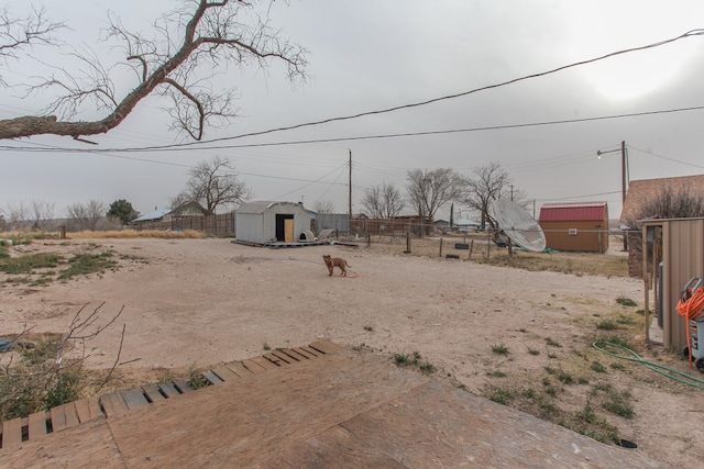 view of yard with a storage shed, an outdoor structure, and fence