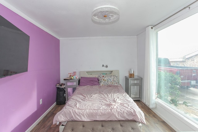 bedroom with crown molding, wood finished floors, and baseboards