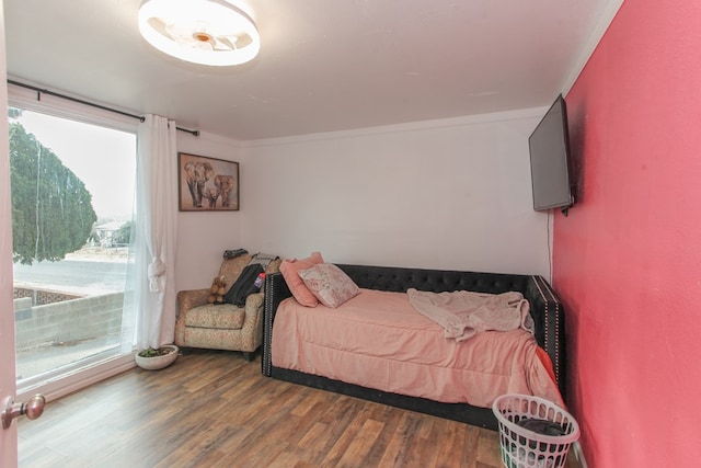 bedroom with wood finished floors and ornamental molding