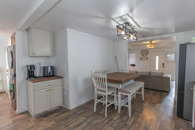 dining space featuring dark wood-style floors, visible vents, crown molding, and baseboards