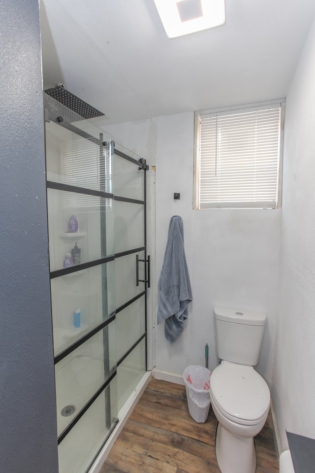 bathroom featuring a stall shower, toilet, baseboards, and wood finished floors