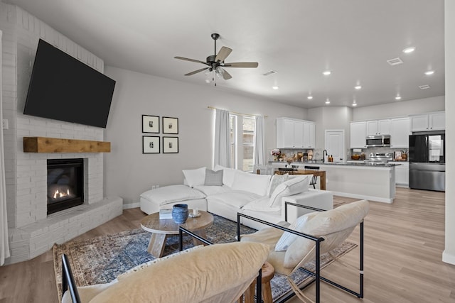 2906 Yellowstone Ct, Midland, TX 79705 - living room with light wood-style floors, a ceiling fan, a brick fireplace, recessed lighting, and baseboards