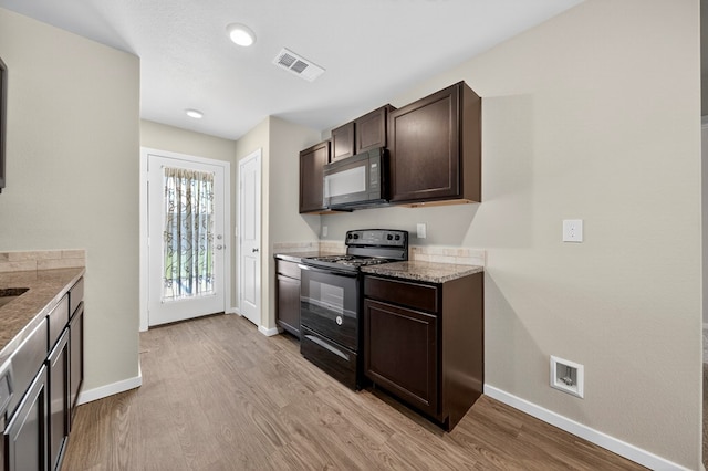 1317 Masquerade Blvd, Odessa, TX 79765 - kitchen with black appliances, dark brown cabinets, light wood-style floors, light stone counters, and recessed lighting