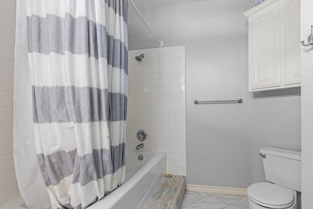 bathroom with marble finish floor, shower / tub combo, toilet, and baseboards