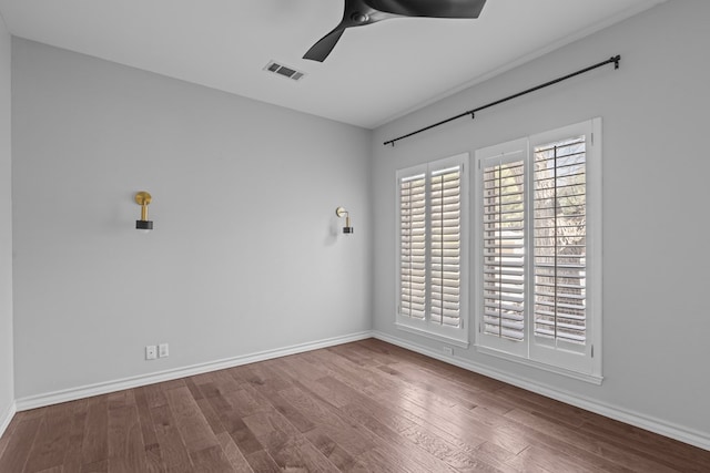 spare room with a ceiling fan, visible vents, baseboards, and wood finished floors