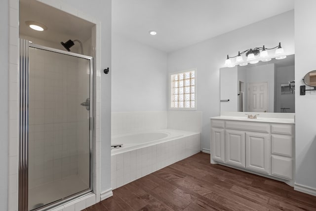 bathroom featuring a garden tub, a shower stall, vanity, and wood finished floors