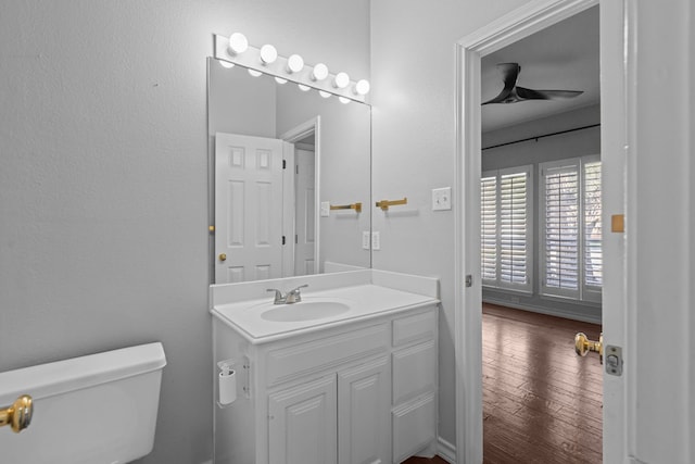 half bath with ceiling fan, vanity, wood finished floors, and toilet