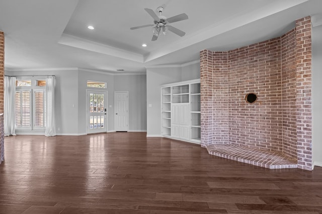 unfurnished living room with baseboards, a raised ceiling, a ceiling fan, wood finished floors, and crown molding