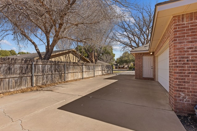 view of patio / terrace with driveway, an attached garage, and fence