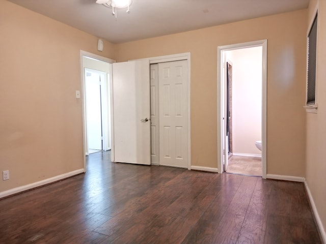 unfurnished bedroom featuring ensuite bath, dark hardwood / wood-style flooring, and a closet