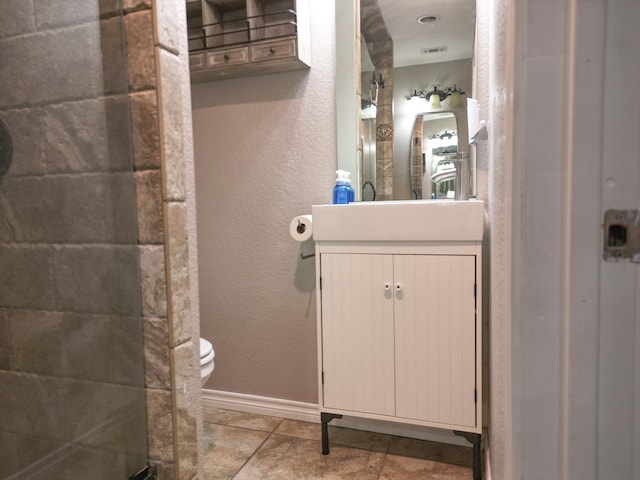 bathroom with tile patterned flooring, vanity, walk in shower, and toilet