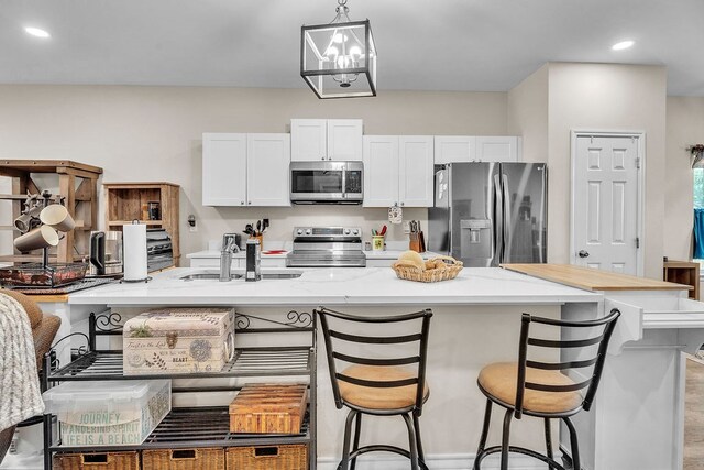 1404 Marijo, Big Spring, TX 79720 - kitchen with appliances with stainless steel finishes, white cabinets, a breakfast bar, decorative light fixtures, and recessed lighting