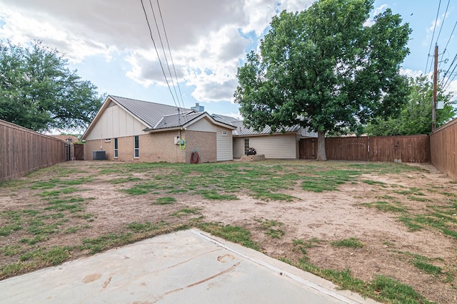 4404 Westminister Dr, Midland, TX 79707 - rear view of house with a fenced backyard, central air condition unit, board and batten siding, brick siding, and metal roof