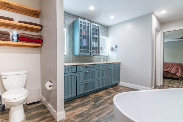 4404 Westminister Dr, Midland, TX 79707 - full bathroom featuring wood finished floors, recessed lighting, toilet, baseboards, and a freestanding tub