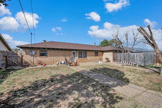 back of house featuring a fenced backyard and brick siding