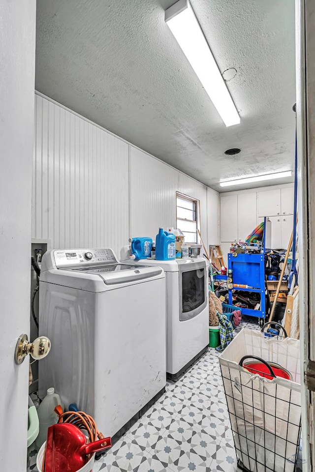 clothes washing area with washing machine and clothes dryer, laundry area, light floors, and a textured ceiling