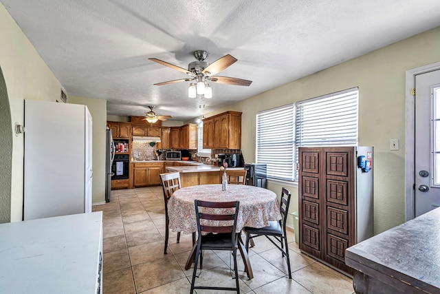 dining area featuring a textured ceiling, light tile patterned flooring, and a ceiling fan