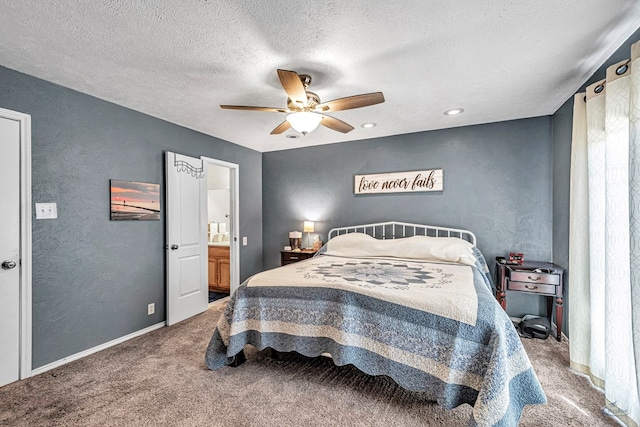 carpeted bedroom with a ceiling fan, a textured ceiling, ensuite bath, baseboards, and a textured wall