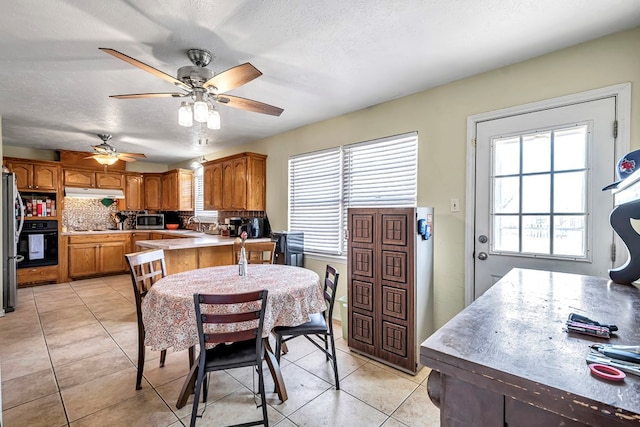 dining space with light tile patterned flooring, a textured ceiling, and a ceiling fan