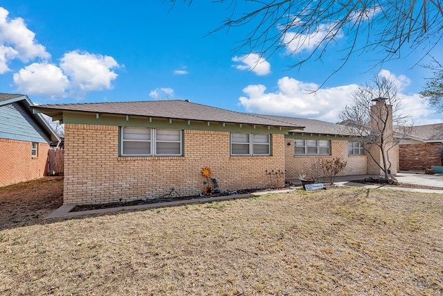 back of house featuring a yard, brick siding, and fence