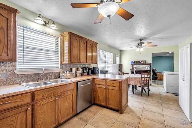 kitchen with light tile patterned floors, a peninsula, ceiling fan, a sink, and dishwasher