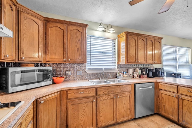 kitchen with plenty of natural light, stainless steel appliances, a ceiling fan, and a sink