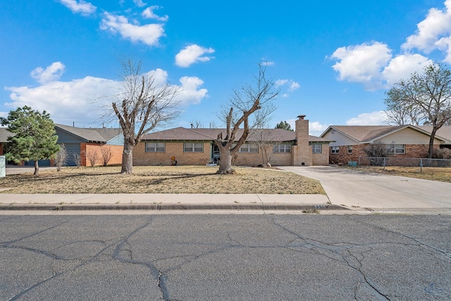 single story home with driveway, a chimney, and fence