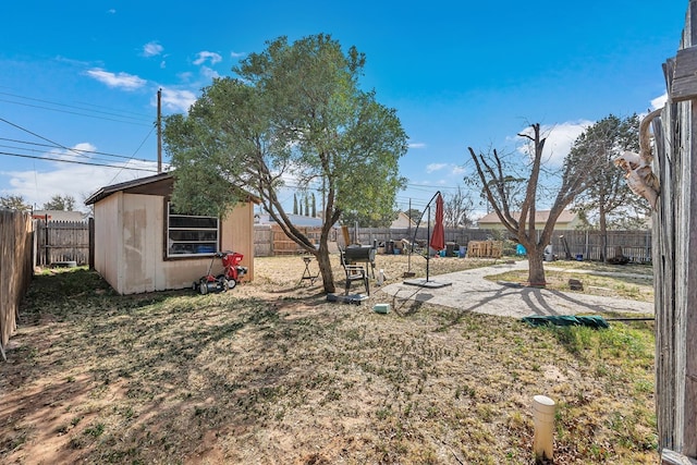 view of yard with an outdoor structure, a fenced backyard, a shed, and a patio