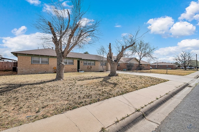 ranch-style home with brick siding, concrete driveway, and fence