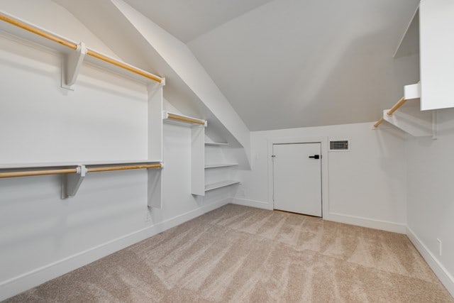 spacious closet featuring lofted ceiling and light colored carpet