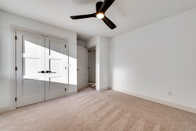 unfurnished bedroom with light colored carpet, ceiling fan, and a closet