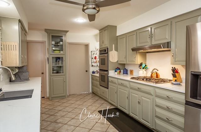 kitchen featuring under cabinet range hood, appliances with stainless steel finishes, light countertops, and a sink