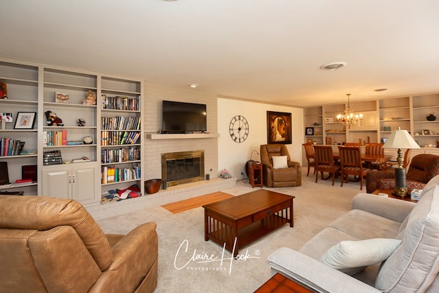 living room with built in shelves, a notable chandelier, visible vents, a brick fireplace, and carpet flooring